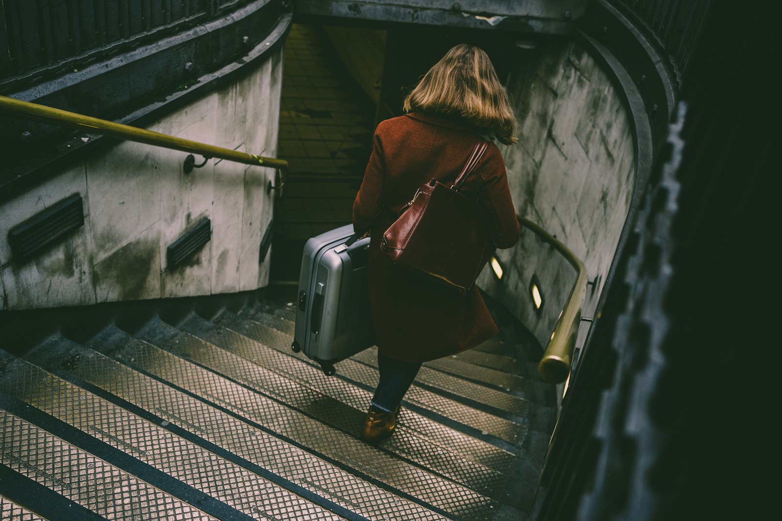 A traveler descending station stairs with a suitcase